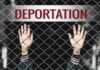 Hands gripping chain-link fence with deportation sign