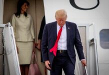 Sudden Schedule Shake-Up: What Spooked Trump? man in suit with red tie walking down airplane stairs