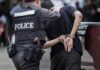 Lottery Windfall, Wild Downfall Continues Police officer escorting handcuffed man to a vehicle