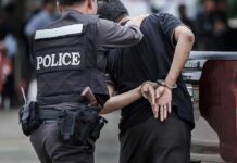Lottery Windfall, Wild Downfall Continues Police officer escorting handcuffed man to a vehicle
