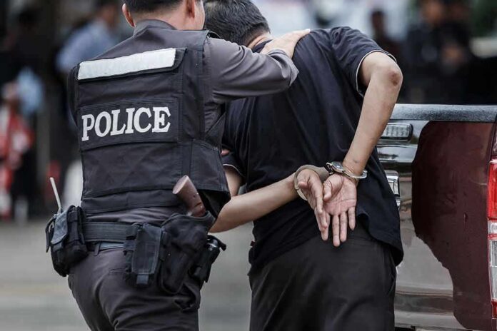 shutterstock_693957643 Police officer escorting handcuffed man to a vehicle