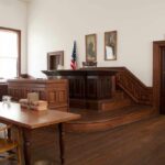 Interior of a historic courtroom with wooden furniture and an American flag