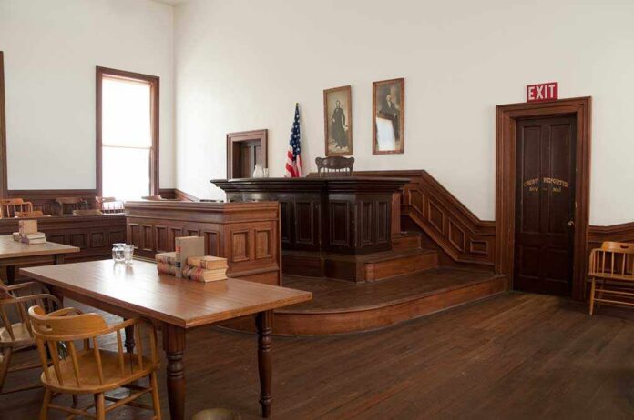 Interior of a historic courtroom with wooden furniture and an American flag