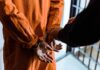 Coach’s Hidden Camera Sparks MAX Sentence Prisoner in orange jumpsuit handcuffed by officer
