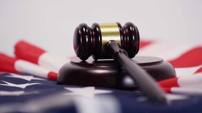 shutterstock_1050534611 Judge’s gavel on a base over an American flag