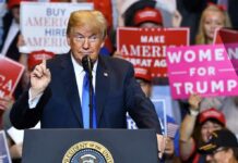 Massive Crowd, One Blunt Demand Donald Trump speaking at a rally podium with crowd holding signs