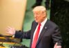 Donald Trump speaking at a podium with arms outstretched