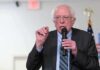 Bernie Sanders speaking into a microphone at an indoor event