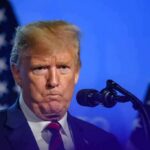 Doxxing Drama: Republicans Turn On Trump Donald Trump at a podium with U.S. flags in the background