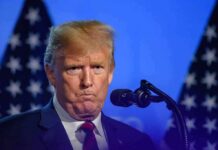 Doxxing Drama: Republicans Turn On Trump Donald Trump at a podium with U.S. flags in the background