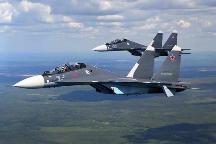 Two fighter jets flying in formation over landscape