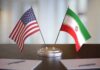 Foreign Guard Meddles – Targets Trump Voters United States and Iran desk flags on a stand