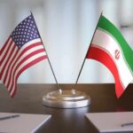 Foreign Guard Meddles – Targets Trump Voters United States and Iran desk flags on a stand