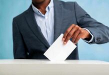 Person in suit casting a ballot into a box