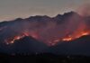 Wildfire burning along mountain slopes at dusk