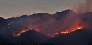 Wildfire burning along mountain slopes at dusk
