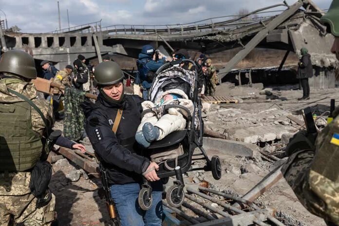 shutterstock_2133927693 Rescuers carry a baby in a stroller through a destroyed bridge