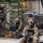 Quadcopter drone flying near camouflaged soldiers outdoors