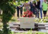 White coffin with red flowers at outdoor burial