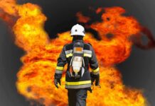 Firefighter in protective gear facing large flames