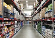 The Hidden Tax Lurking Inside Cross-Border Trade Warehouse aisle with tall shelves stacked with boxes and bulk goods