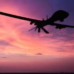 Domestic Shield Ramps Up – Why Now? drone silhouette flying against a pink and purple sunset sky