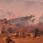 Wildfire burns on hillside near suburban homes