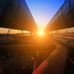 Oil Lifeline Hit Again – Brace For Pain Industrial pipelines at sunset
