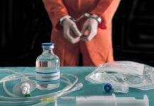 Tennessee Tried Twice. She Was Still Alive Handcuffed person in orange jumpsuit behind medical vials and IV equipment