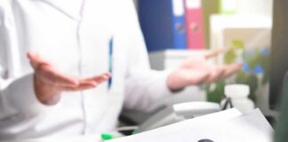 Doctor gesturing during consultation with patient holding paper with question mark