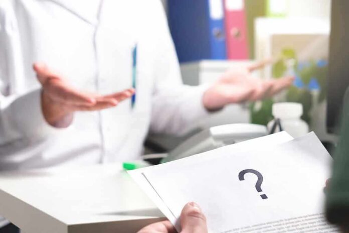 shutterstock_788107000 Doctor gesturing during consultation with patient holding paper with question mark