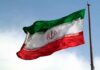 Iranian flag flying against a clear sky.