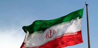 Iranian flag flying against a clear sky.
