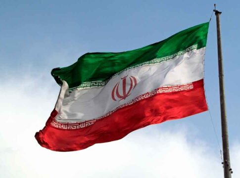 Iranian flag flying against a clear sky.