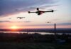 Drones flying at sunset over a landscape.