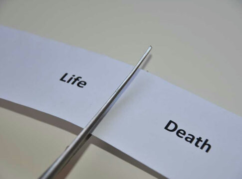 Scissors cutting paper labeled Life and Death