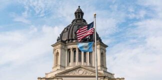 South Dakota Capitol building with American and state flags.