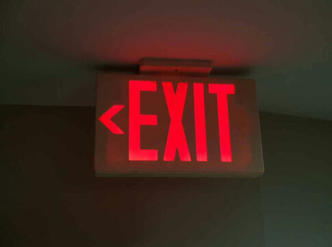 Red illuminated exit sign with left arrow.