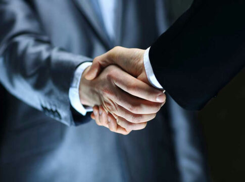 Two individuals in suits shaking hands firmly.