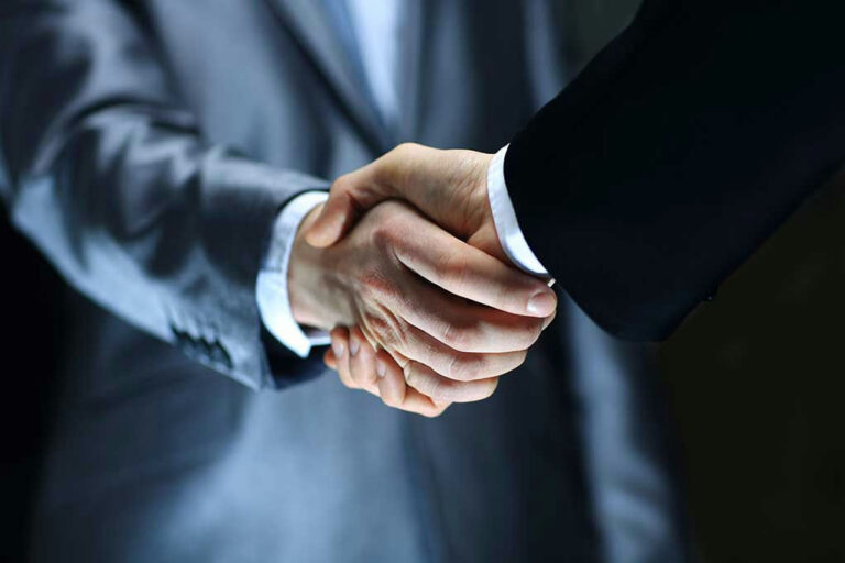 Two individuals in suits shaking hands firmly.