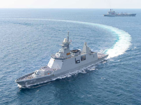 Warships maneuvering at sea, leaving a white wake.