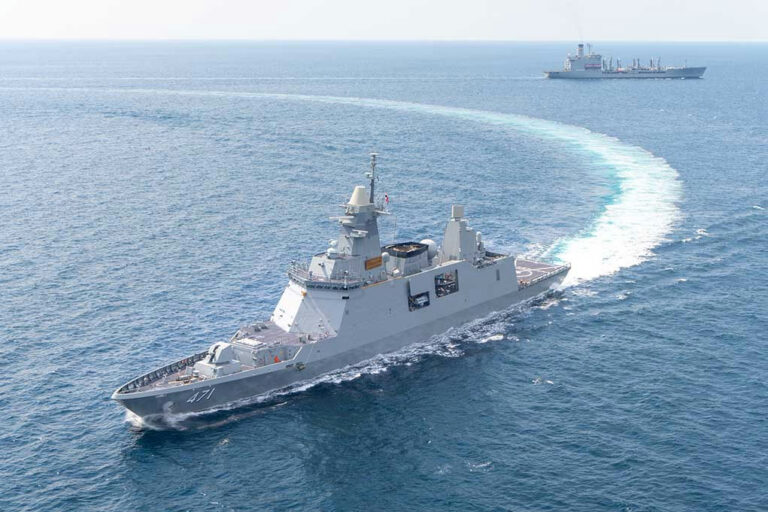 Warships maneuvering at sea, leaving a white wake.