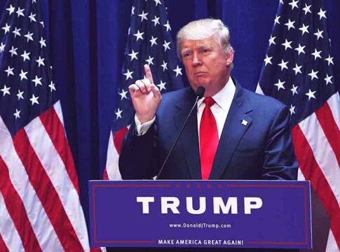 Politician speaking at podium with American flags behind.