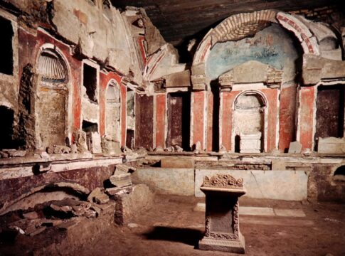 Interior view of an ancient burial chamber with frescoes and stone structures