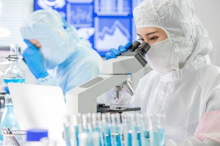 Scientists examining samples under microscopes in a laboratory.