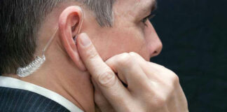 Man wearing earpiece adjusting it with finger.