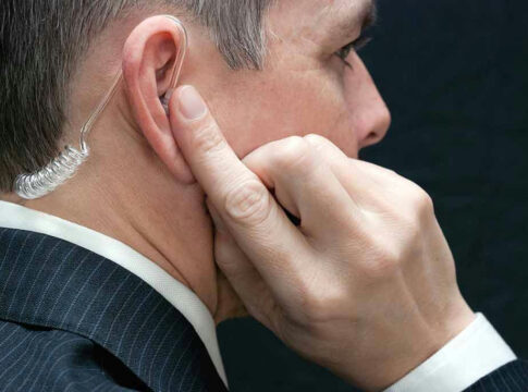 Man wearing earpiece adjusting it with finger.
