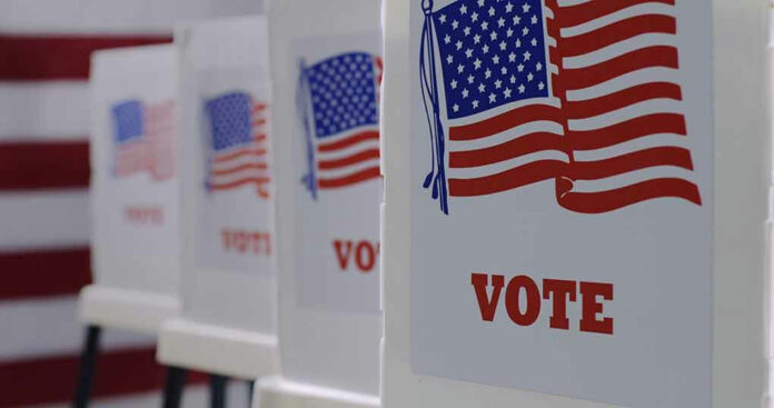 1743370412 Voting booths with American flags and VOTE signs