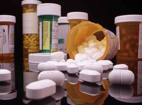 Assorted prescription pill bottles and tablets scattered.