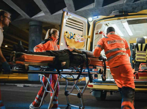 Paramedics loading patient into ambulance at night.
